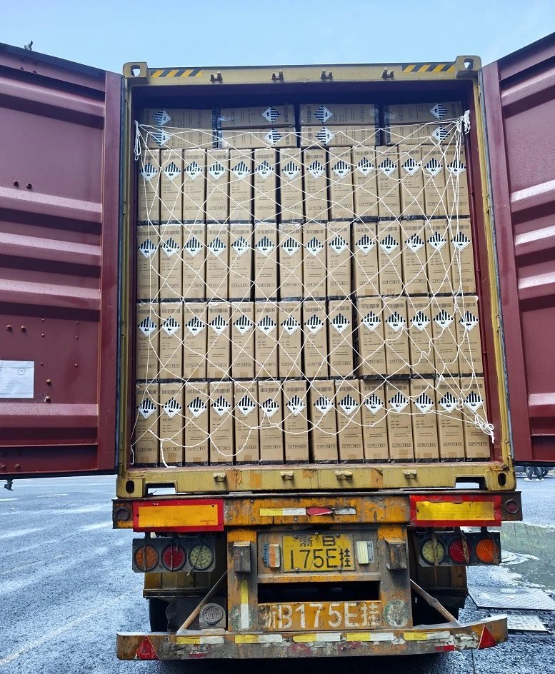 Export container loaded floor to ceiling with cartons carrying Class 9A lithium battery labels, secured with a cargo net