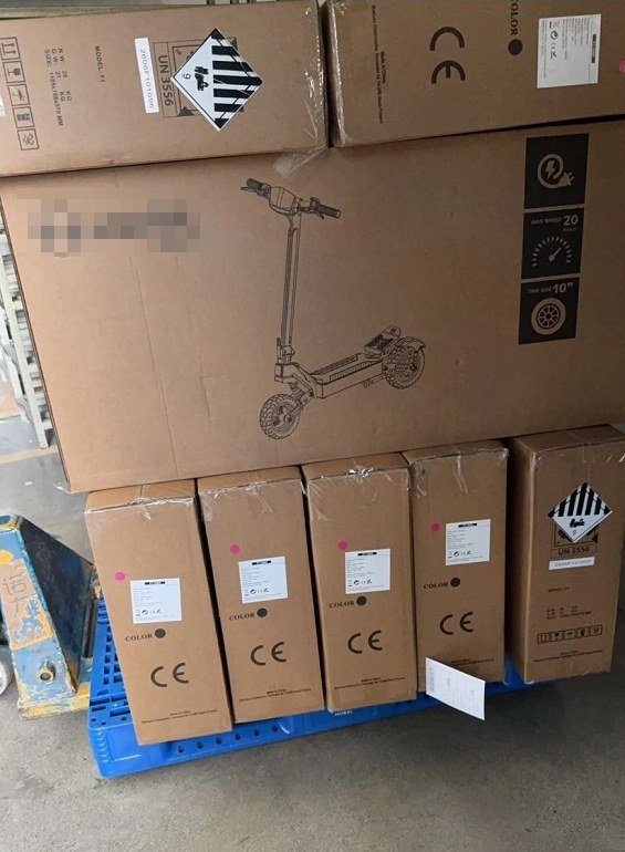 Electric scooter cartons on a pallet marked UN 3556 for lithium-ion battery powered vehicles, alongside CE marking